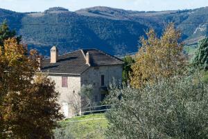 una vecchia casa su una collina con montagne sullo sfondo di Agriturismo La Malcontenta e il Lupo a Todi