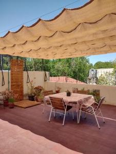 un patio con mesa y sillas bajo una sombrilla grande en Josefa - Departamento con terraza y parrila en Mendoza
