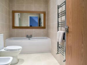 a bathroom with a tub and a toilet and a mirror at ThreeStorey Townhouse - Free parking in Normanton +18 photos