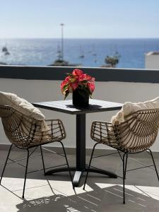 een tafel met twee stoelen en een vaas met rode bloemen bij Boutique studio, sea views of Las Vistas and free wifi in Playa de las Americas