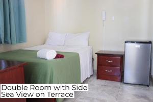 a bedroom with a bed with a green blanket and a refrigerator at Hotel Enrique II Zona Colonial, Bed and Breakfast in Santo Domingo