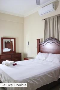1 dormitorio con 1 cama blanca grande y espejo en Hotel Enrique II Zona Colonial, Bed and Breakfast, en Santo Domingo
