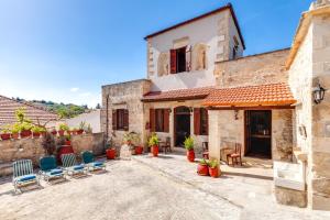 un patio de una casa con sillas y mesas en Traditional Home Vereniki With Heated Pool - BY APOKORONAS VILLAS, en Gavalochori