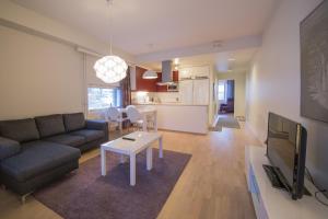 a living room with a couch and a tv and a table at Kotimaailma Apartments Turku in Turku