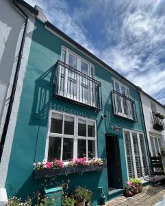 布萊頓霍夫的住宿－Charming BRIGHTONMEWS cottage parking 1min to sea&shops，蓝色的建筑,有白色的窗户和鲜花