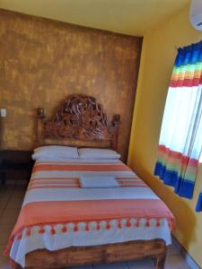 a bed in a bedroom with a wooden headboard at HOTEL ESTRELLA HUASTECA in Aquismón