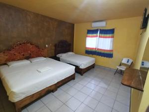 a hotel room with two beds and a window at HOTEL ESTRELLA HUASTECA in Aquismón