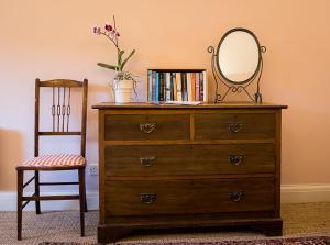 a dresser with a mirror on top of it and a chair at Stylish bolthole in the heart of the Meon Valley in East Meon