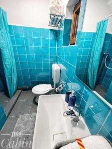 TINY CABIN في براشوف: حمام من البلاط الأزرق مع حوض استحمام ومرحاض