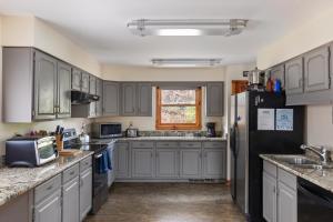 a kitchen with gray cabinets and a black refrigerator at Sleepy Hollow 5BR Cabin - National Park 7 Min, Hot Tub, Fire Pit, Sleeps 12 in Luray