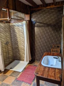 a bathroom with a shower with a sink and a table at Les Acacias Bungalows in Manambato