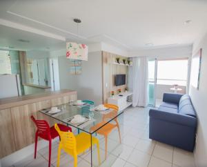 - un salon avec une table, des chaises et un canapé dans l'établissement Apartamento Encantador Verano na Praia, à Natal