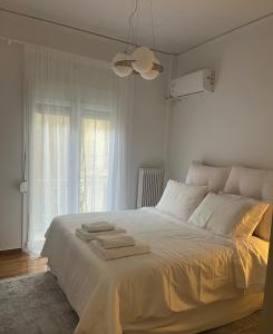 Un dormitorio con una cama blanca con toallas. en Alex’s home next to Laiko, en Atenas