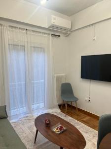 een woonkamer met een tv en een bank en een tafel bij Alex’s home next to Laiko in Athene