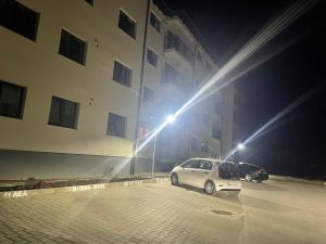 un coche blanco estacionado frente a un edificio por la noche en TAJ en Ipoteşti