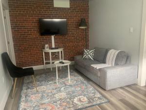 uma sala de estar com um sofá e uma televisão numa parede de tijolos em Station 1 by Terra Hospitality em Moncton