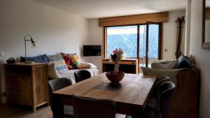 uma sala de estar com uma mesa e um sofá em Le Soladret - 2 pièces 4 étoiles - Vue extraordinaire sur les Aravis em La Clusaz