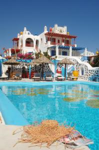 a swimming pool with blue water and white buildings at Sun of Mykonos Studios in Klouvas