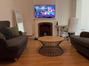 a living room with a table and a tv on a fireplace at Entire -4 Bedrooms Detached House with Driveway in Nottingham