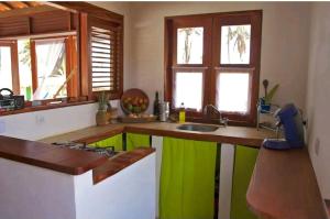 a kitchen with green and white counters and windows at Casinha do Cauipe in Caucaia
