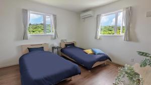 2 camas en una habitación con 2 ventanas en 【KouriGarden】古宇利島の海と緑と星を眺める一棟貸切別荘ヴィラ, en Nakijin