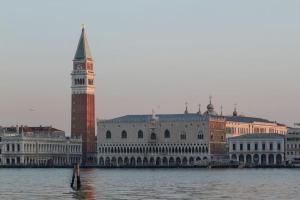 un grande edificio con torre dell'orologio accanto all'acqua di Bauhaus Venice Apartment a Venezia