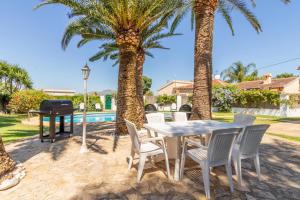 een patio met een tafel en stoelen en palmbomen bij Casa Segaria in Denia
