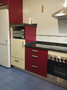 Precioso piso con ducha hidromasaje VUT-LE-726 في أستورغا: مطبخ مع دواليب حمراء وثلاجة بيضاء