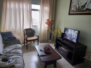 ein Wohnzimmer mit einem Sofa und einem TV in der Unterkunft Edifício Galassi in Praia Grande