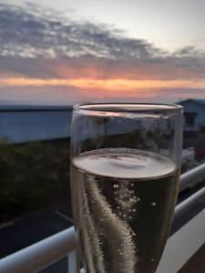 a glass of wine sitting on a balcony with the sunset at BLUE SUMMER T3 - vue sur mer - Saint Gilles les Bains in Saint-Gilles les Bains