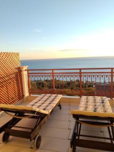 twee banken op een balkon met de oceaan op de achtergrond bij Villa Panorama in Lourdhata