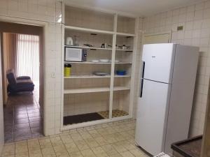 een keuken met een witte koelkast in de kamer bij Apto Praia Gonzaga - melhor localização in Santos