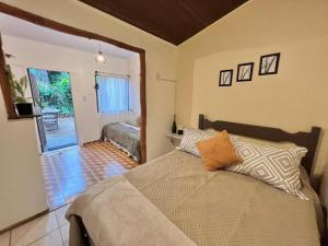 1 dormitorio con 1 cama y puerta que da a un patio en Coco Suites en Abraão