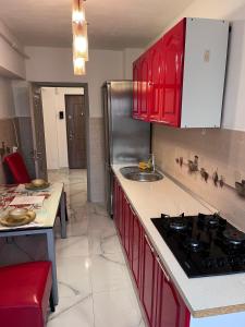 a kitchen with red cabinets and a sink and a stove at Apartament In Centrul Orasului in Bacău