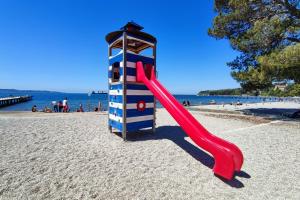 a red slide on the beach next to a lighthouse at New Apartments Škofije Ankaran in Koper