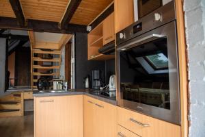 eine Küche mit Holzschränken und Edelstahlgeräten in der Unterkunft Poezelhoekvallei appartement in Zonnebeke