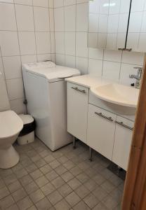 a white bathroom with a toilet and a sink at Mäntymajat in Äkäslompolo