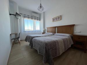 a bedroom with two beds and a chair and a window at Hostal Parador de los Llanos in Torreorgaz