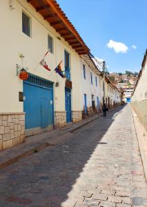 a person walking down a cobblestone street with buildings at Hostal Cusco de mis Sueños in Cusco