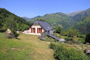 una pequeña casa en una colina con montañas en el fondo en L'espiatet en Borce
