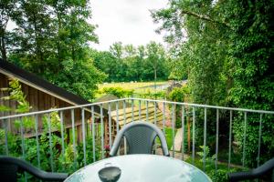 a table on a balcony with a view of a garden at Poezelhoekvallei appartement in Zonnebeke