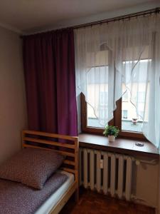 um quarto com uma cama e duas janelas com cortinas em Mieszkanie na Mickiewicza 7 em Olkusz
