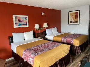 two beds in a hotel room with red walls at Budget Host Inn in Greenup