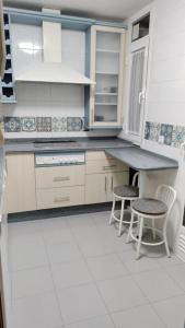a kitchen with a counter and two chairs in it at PUERTA BAHÍA, Parking privado in Jerez de la Frontera