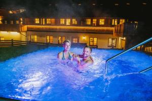 two men are sitting in a hot tub at night at Aparthotel Hummerau in Alpbach