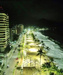a beach with palm trees and the ocean at night at Pausa da Correria nesta estadia I in Caraguatatuba