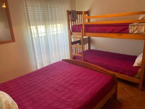 een slaapkamer met 2 stapelbedden met paarse lakens bij t2 armação de pêra in Armação de Pêra