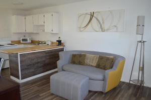 a living room with a chair and a kitchen at Travelodge by Wyndham Colorado Springs Airport/Peterson AFB in Colorado Springs