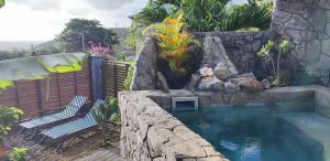 a swimming pool with a rock wall and a swimming poolituresitures at Sunset Sapphire in Case-Pilote