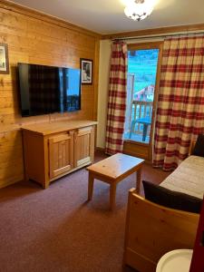 ein Wohnzimmer mit einem Flachbild-TV und einem Sofa in der Unterkunft Les alpages location appartement 108 in Lanslebourg-Mont-Cenis